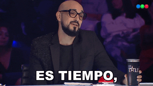 a man with glasses and a beard is holding a cup that says y dedicacion on it