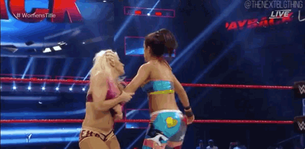 two women are wrestling in a wrestling ring and one is wearing a bikini .