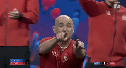 a man in a red shirt is pointing at the camera during a game