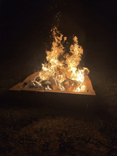a large fire is burning in a wooden box in the dark
