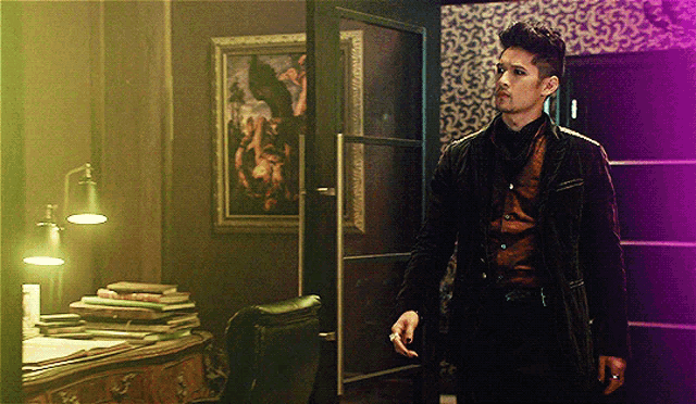 a man in a black jacket is standing in a room