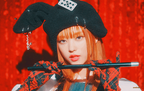 a woman with red hair is holding a cane and wearing a hat with a card on it