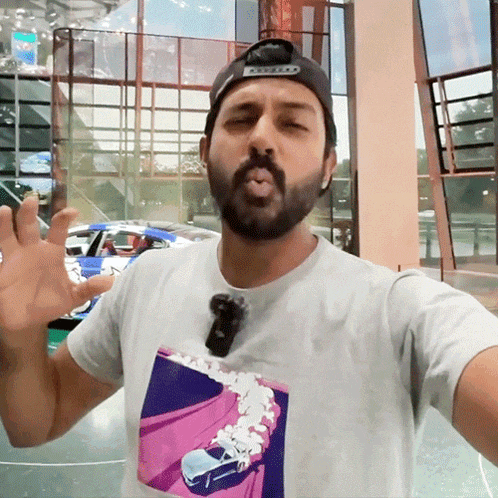 a man wearing a white shirt with a picture of a car on it takes a selfie