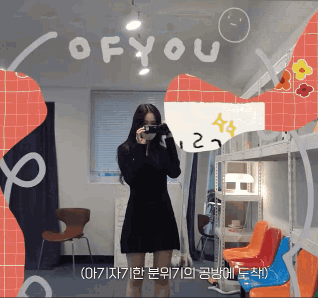 a girl in a black dress taking a picture of herself in front of a sign that says ' of you '