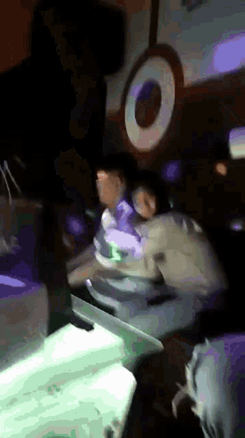 a group of people are dancing in a dark room with a circle in the background