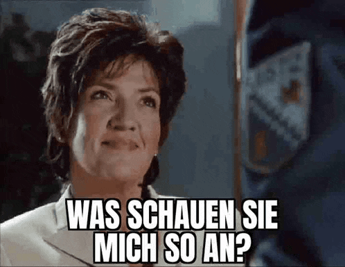 a woman in a suit is talking to a police officer and says was schauen sie mich so an .