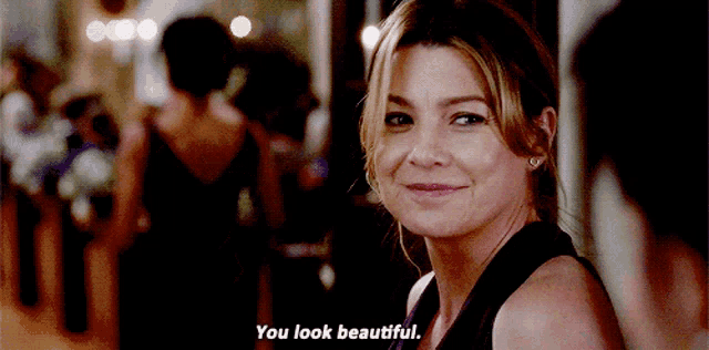 a woman in a black dress is smiling and says " you look beautiful "