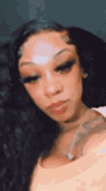 a close up of a woman 's face with long hair and a tattoo on her arm .