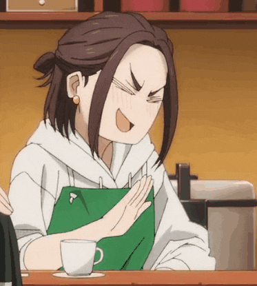 a woman wearing a green apron is sitting at a table with a cup of coffee in front of her