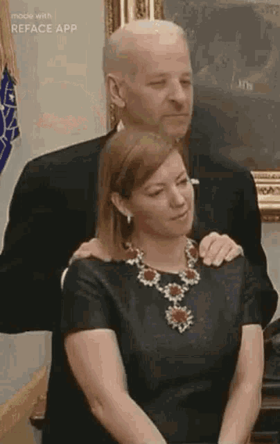 a man and a woman are hugging each other in a room . the woman is wearing a necklace .
