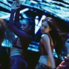 a group of women are dancing on a stage in front of a large screen .
