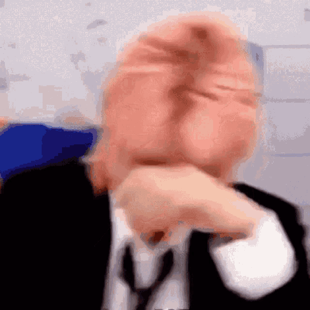 a blurry picture of a man in a suit and tie making a face .