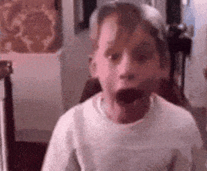 a young boy is making a surprised face in a room .
