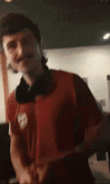 a man wearing headphones and a red shirt with a white emblem on it