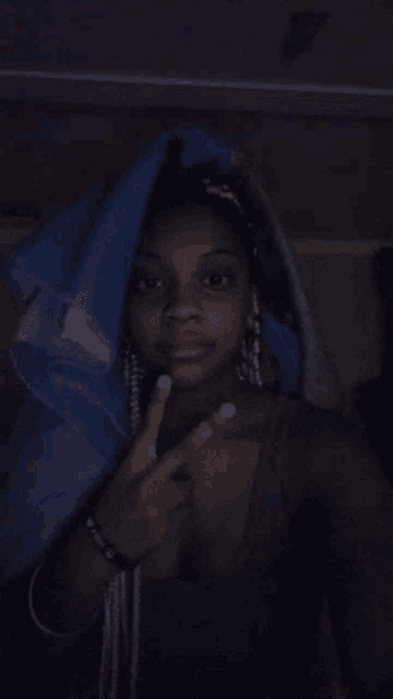 a woman covering her head with a blue blanket and giving the middle finger