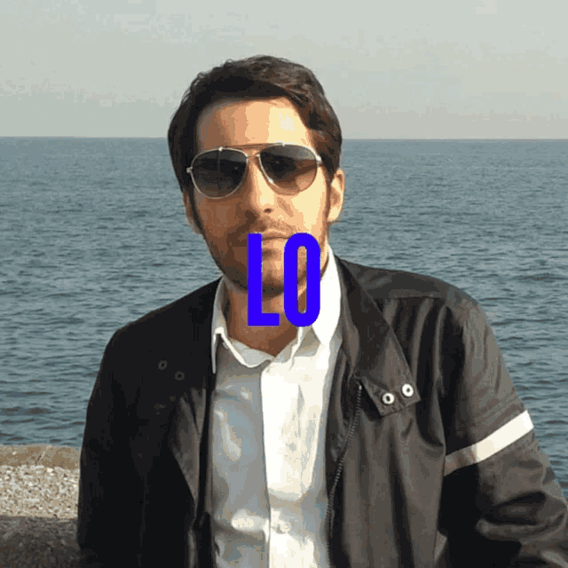 a man wearing sunglasses and a jacket with the letter l on his face