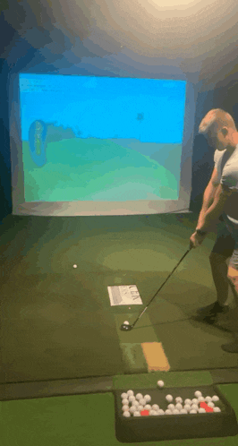 a man is swinging a golf club at a golf ball in a simulator .