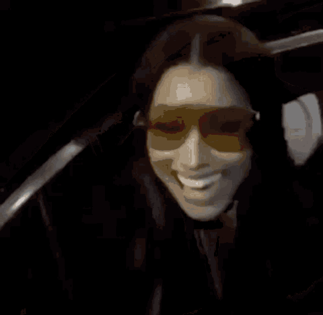 a woman wearing sunglasses is sitting in a car holding a teddy bear and smiling .