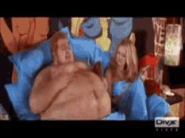 a fat man is laying on a bed next to a woman with divx written on the bottom of the screen