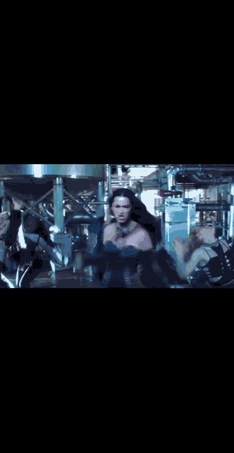 a group of women are dancing in a dark room with pipes in the background