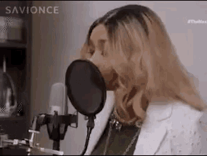 a woman is singing into a microphone with her mouth open .