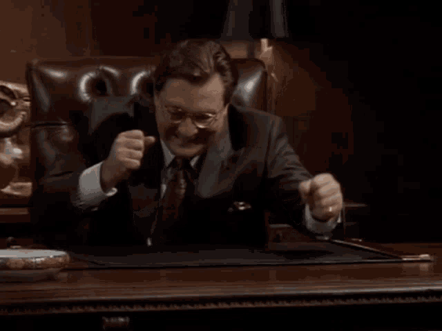 a man in a suit and tie sitting at a desk