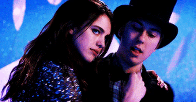 a man and a woman are standing next to each other and the woman is wearing a top hat .