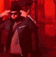 a man in a black jacket is standing in front of a row of red lights