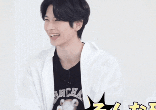 a young man in a white shirt is smiling with a black t-shirt on