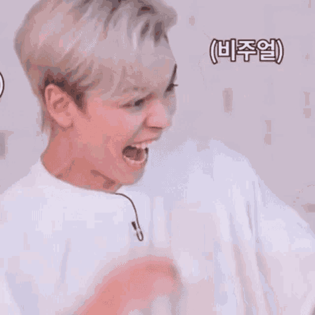 a young man with blonde hair is making a funny face with his mouth open .