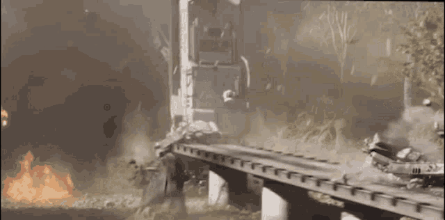 a train is going over a bridge with smoke coming out of it and a fire in the background .