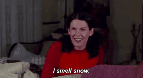 a woman in a red sweater is sitting on a couch and saying `` i smell snow '' .