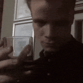 a close up of a man holding a glass in front of his face