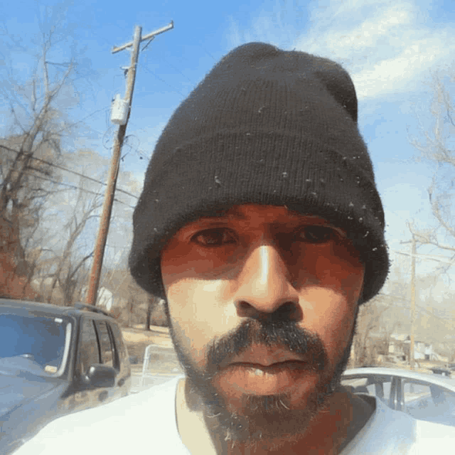 a man with a beard wearing a black beanie and a white shirt