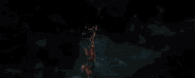 a man in a black suit is holding a torch in a dark room .
