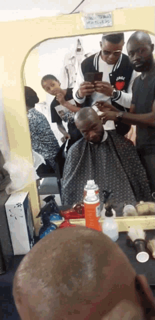 a man is getting his hair cut in front of a mirror with a sign that says " no smoking " on it