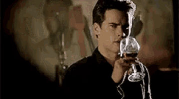 a man is holding a glass of red wine in his hand .