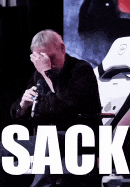 a man covering his face while holding a microphone with the word sack above him