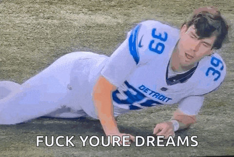 a football player is laying on the ground with the words `` fuck your dreams '' written above him .