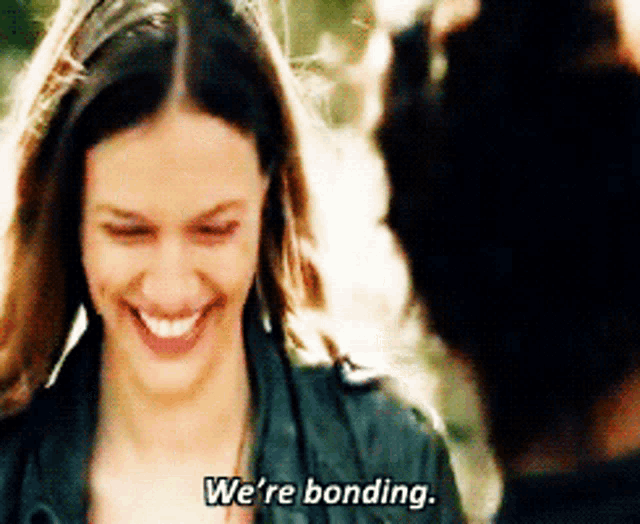 a woman in a black jacket is smiling and says we 're bonding