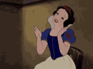 snow white from disney 's snow white and the seven dwarfs is sitting on a chair waving her hands .