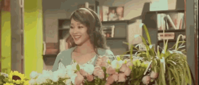 a woman is standing in front of a bunch of flowers in a store .