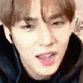 a close up of a young man 's face with his mouth open and his tongue sticking out .