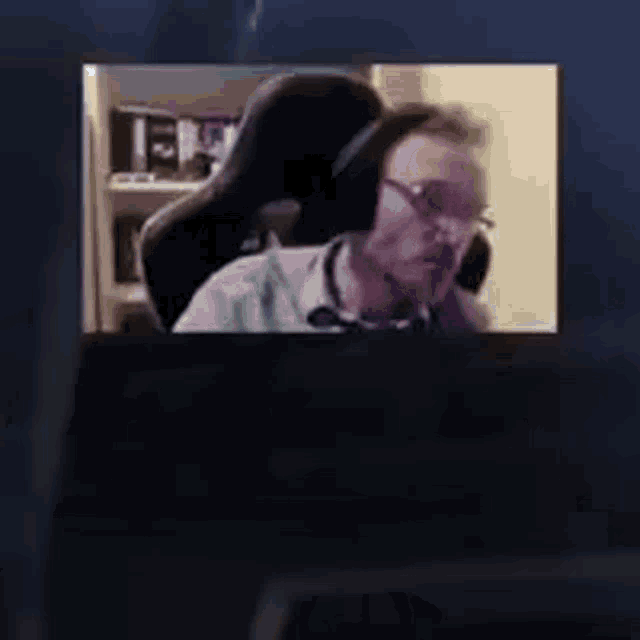 a man is sitting in a chair in front of a computer screen .