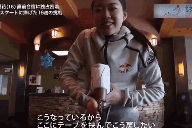 a woman wearing a red bull sweatshirt is smiling