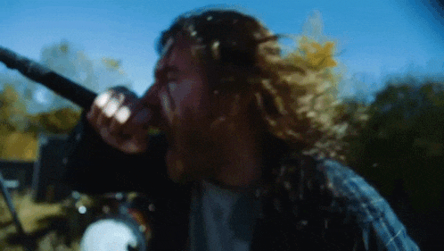 a man singing into a microphone with his hair blowing in the wind .