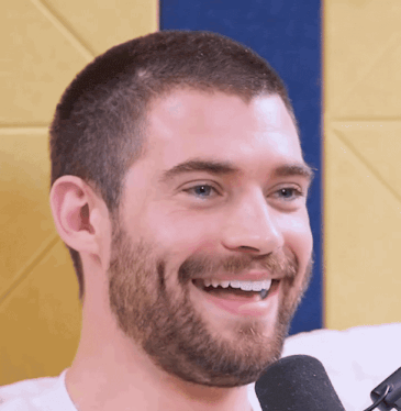 a man with a beard is smiling and looking at the camera