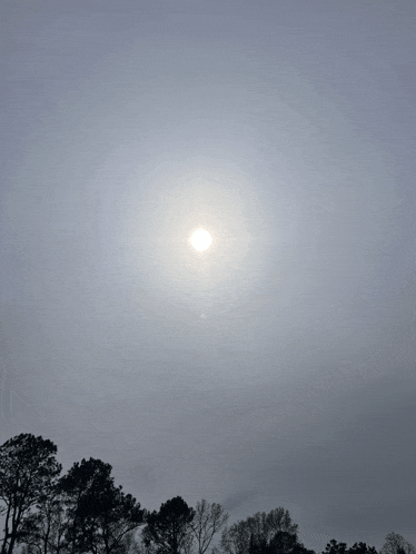 the sun shines brightly through the clouds behind the trees