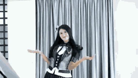 a woman in a military uniform is standing in front of a curtain with her arms outstretched .