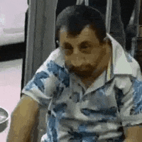 a man with a beard is wearing a blue and white shirt and sitting in a chair .